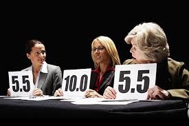 Three judges, each holding up a scorecard. Two are 5.5; third is 10.0